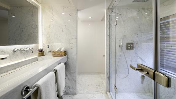 A bathroom clad in light marble with XXL rain shower, double washbasin and large mirror front.